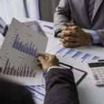 Peace of Mind Business Solutions professionals analyzing financial statements with charts and graphs during a business meeting.